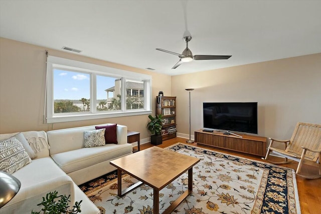 living room featuring visible vents, ceiling fan, baseboards, and wood finished floors