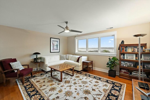 living room with a ceiling fan, baseboards, visible vents, and wood finished floors