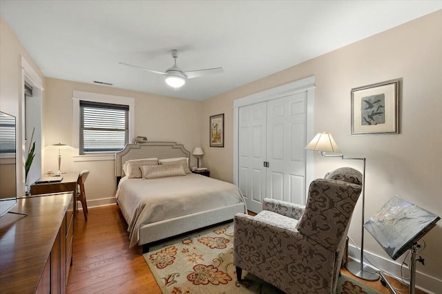 bedroom featuring visible vents, a ceiling fan, baseboards, a closet, and dark wood finished floors