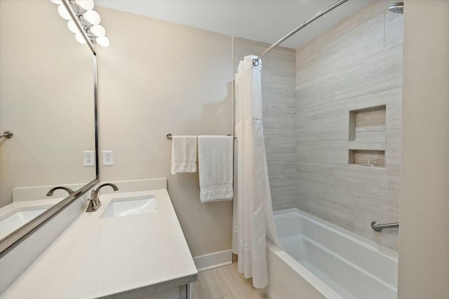 full bath featuring shower / bath combo, wood finished floors, vanity, and baseboards