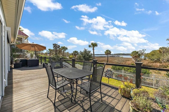 wooden terrace with a water view and outdoor dining space