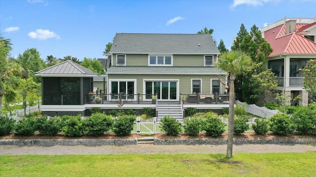 rear view of property with a deck, fence, a sunroom, stairs, and a standing seam roof