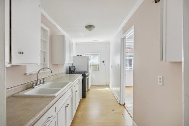 634 Rutledge Ave, Charleston, SC 29403 - kitchen with a sink, stainless steel range with gas stovetop, ornamental molding, light wood-style flooring, and white cabinets