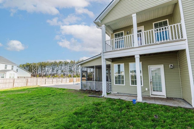 back of house with a balcony, a sunroom, a lawn, and a patio area