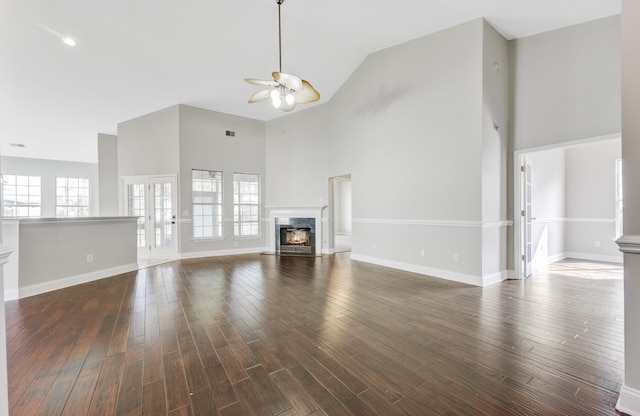 unfurnished living room with high vaulted ceiling, dark wood-type flooring, and a wealth of natural light