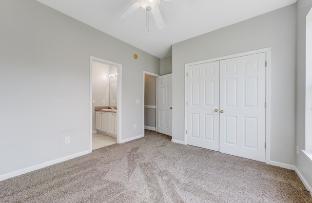 unfurnished bedroom with a closet, light colored carpet, connected bathroom, and ceiling fan