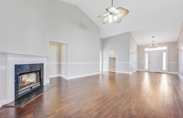 unfurnished living room with a premium fireplace, high vaulted ceiling, dark hardwood / wood-style floors, and ceiling fan with notable chandelier