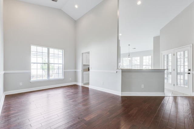 unfurnished living room featuring high vaulted ceiling, a healthy amount of sunlight, and hardwood / wood-style floors