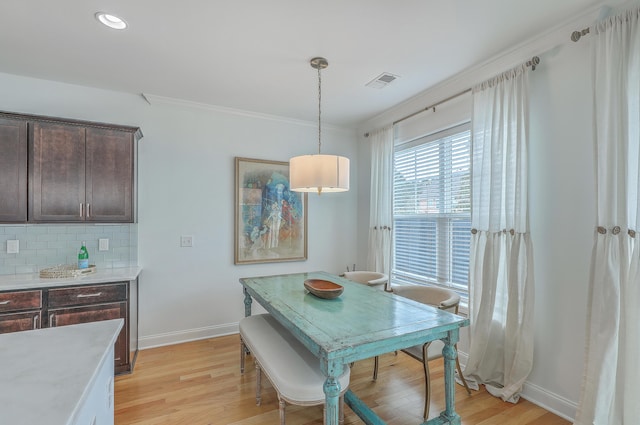 dining room with crown molding and light hardwood / wood-style floors