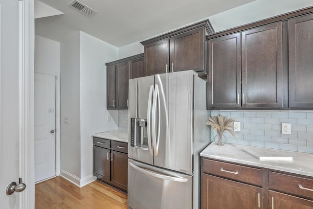 kitchen featuring dark brown cabinetry, stainless steel fridge with ice dispenser, light hardwood / wood-style flooring, and tasteful backsplash