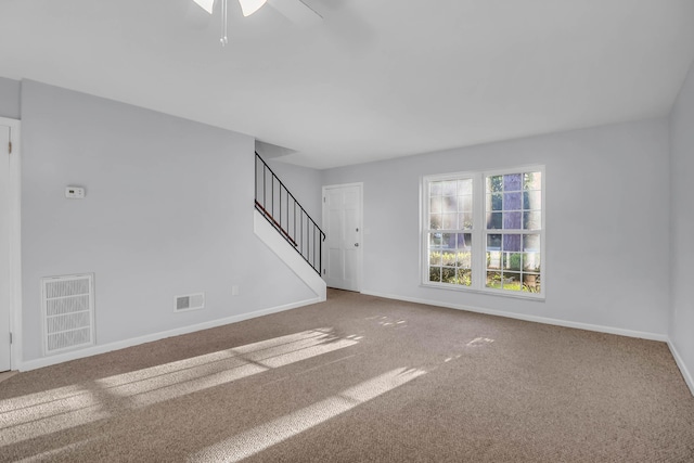unfurnished living room with stairs, carpet flooring, baseboards, and ceiling fan