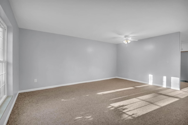carpeted empty room with ceiling fan and baseboards