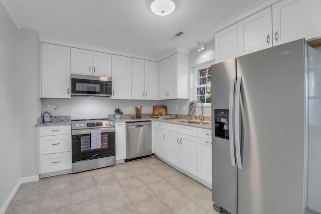 kitchen featuring stainless steel appliances, a sink, white cabinets, and light stone countertops