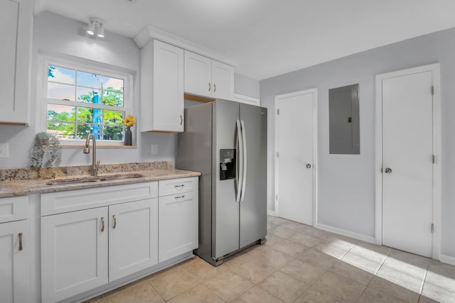 kitchen with stainless steel fridge with ice dispenser, electric panel, white cabinetry, a sink, and light stone counters