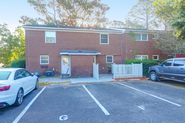 view of building exterior with uncovered parking and fence