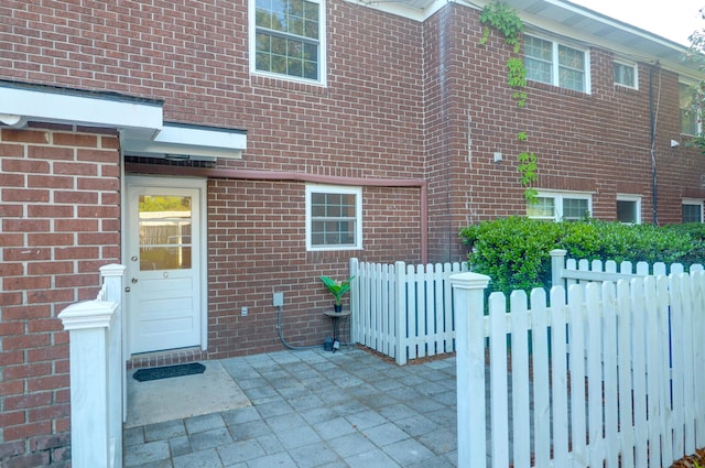 entrance to property with brick siding, fence, and a patio