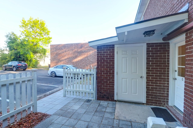 doorway to property with brick siding and uncovered parking