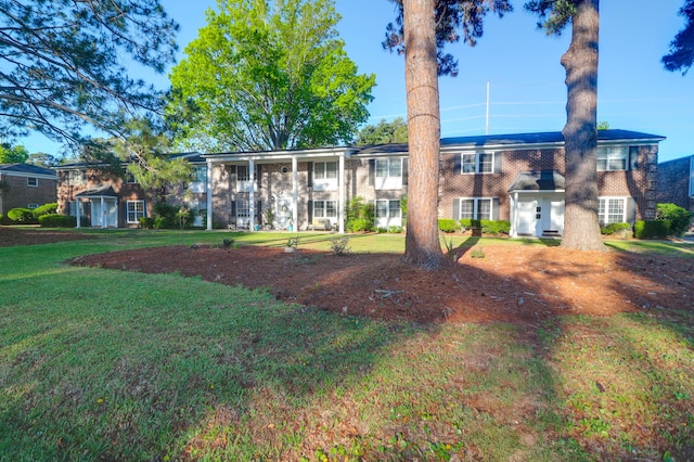 back of property featuring a lawn and brick siding