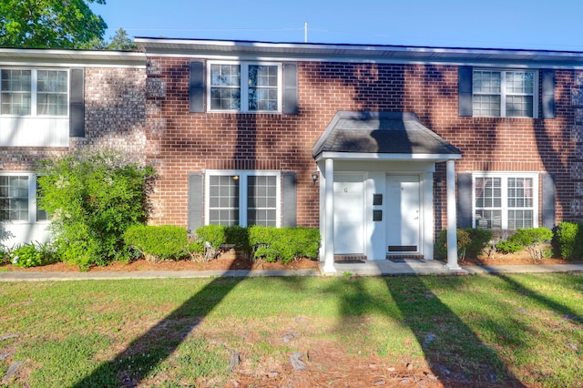 view of property with brick siding and a front lawn