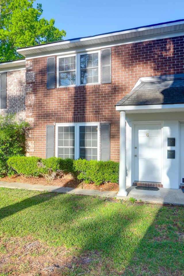 view of front facade with brick siding and a front yard