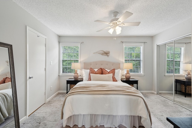 bedroom with carpet, a closet, a textured ceiling, baseboards, and a ceiling fan