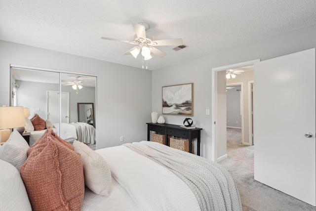 bedroom featuring light carpet, a closet, a ceiling fan, and a textured ceiling