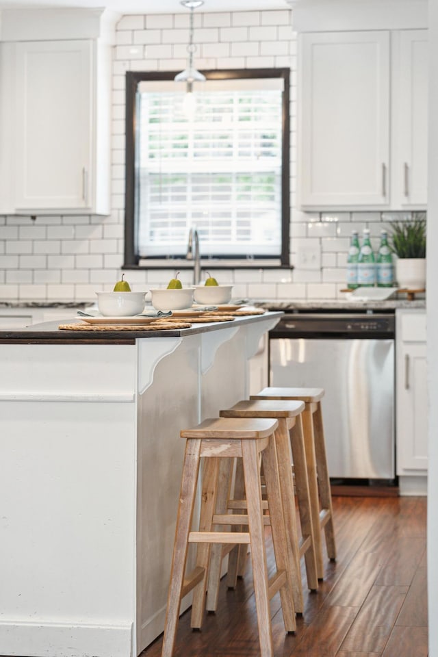 kitchen featuring dishwasher, backsplash, white cabinetry, hanging light fixtures, and dark wood-type flooring
