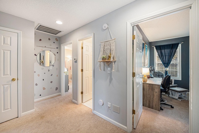 hallway featuring a textured ceiling and light carpet