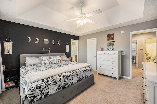 carpeted bedroom with ceiling fan and a raised ceiling