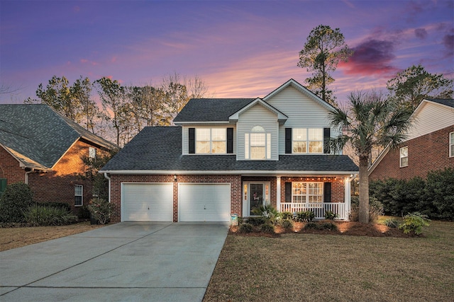 view of front of home with a porch, a lawn, and a garage