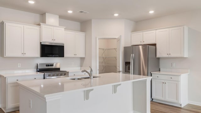 kitchen with stainless steel appliances, white cabinetry, a kitchen island with sink, and sink