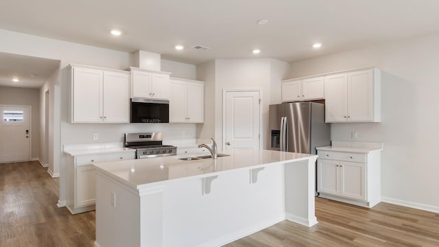 kitchen featuring a kitchen island with sink, sink, white cabinetry, and stainless steel appliances