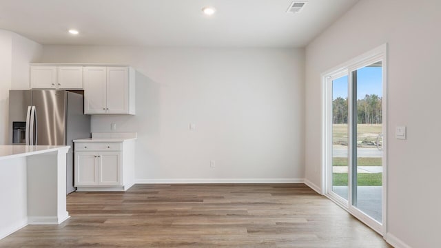 kitchen featuring stainless steel fridge, light hardwood / wood-style floors, and white cabinets