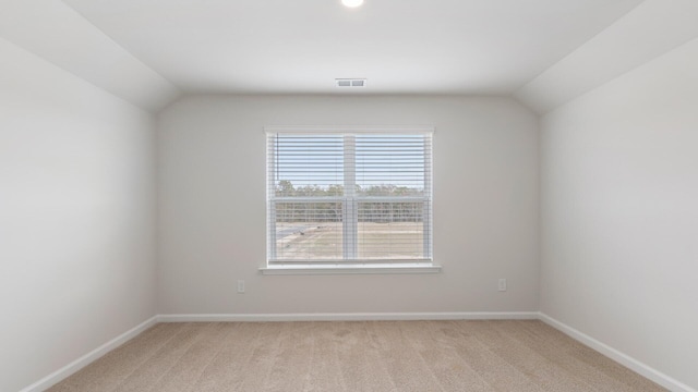 carpeted spare room with vaulted ceiling