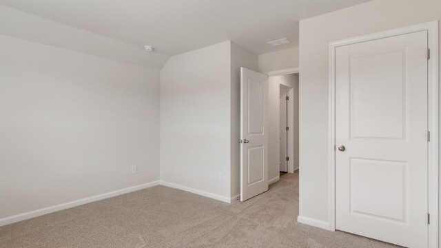 carpeted empty room featuring lofted ceiling