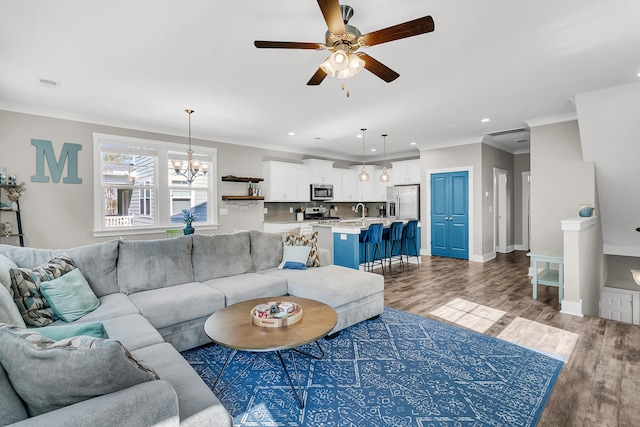 living room featuring crown molding, sink, wood-type flooring, and ceiling fan with notable chandelier