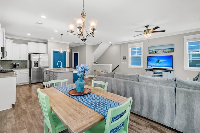 dining space with ceiling fan with notable chandelier, ornamental molding, sink, and dark hardwood / wood-style floors