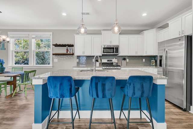 kitchen with a center island with sink, appliances with stainless steel finishes, and white cabinetry