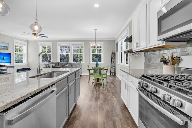 kitchen with white cabinetry, light stone countertops, stainless steel appliances, and sink