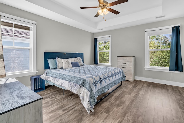 bedroom with a raised ceiling, hardwood / wood-style flooring, and ceiling fan