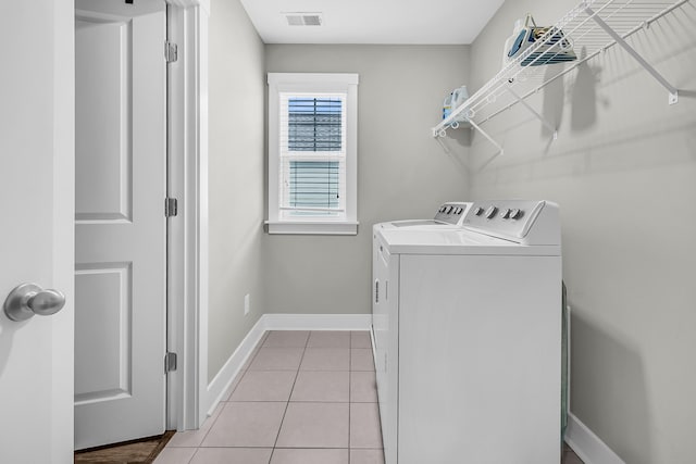 clothes washing area with washing machine and dryer and light tile patterned floors