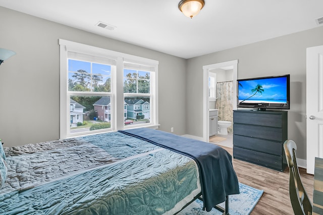 bedroom with connected bathroom and light wood-type flooring