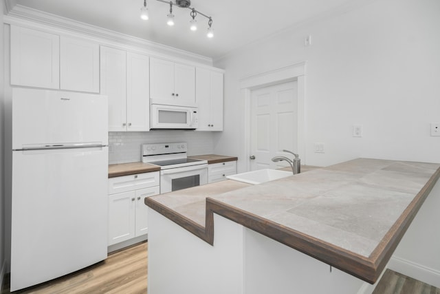 kitchen with kitchen peninsula, decorative backsplash, white appliances, white cabinets, and sink