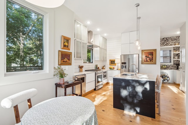 kitchen featuring high end appliances, white cabinetry, sink, and pendant lighting