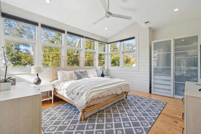 bedroom featuring lofted ceiling, wooden walls, hardwood / wood-style floors, and ceiling fan