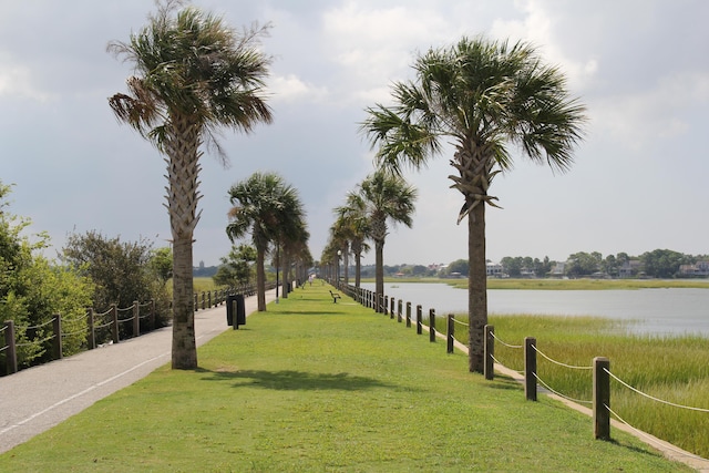 view of property's community with a water view and a lawn