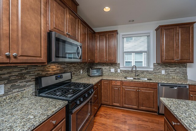 1607 Roustabout Way, Charleston, SC 29414 - kitchen with stainless steel appliances, wood finished floors, light stone counters, backsplash, and crown molding
