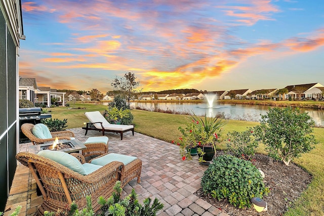 patio terrace at dusk with a yard, a water view, and an outdoor fire pit