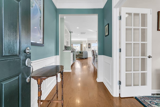 foyer featuring a wainscoted wall, visible vents, dark wood-type flooring, crown molding, and a decorative wall