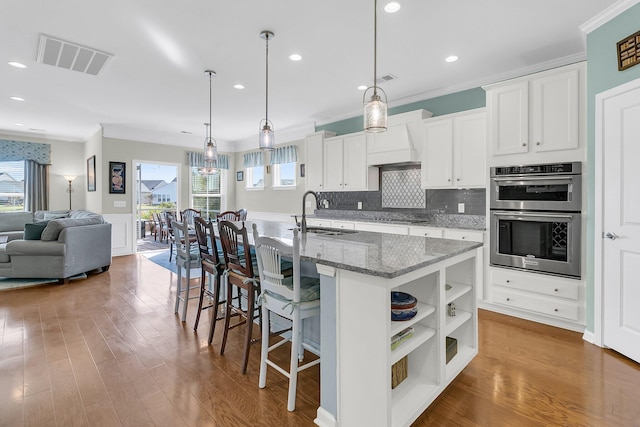 kitchen featuring visible vents, ornamental molding, a sink, double oven, and black cooktop